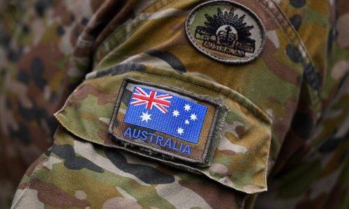 Australian Army camouflage uniform with patches showing the national flag and the Rising Sun emblem.
